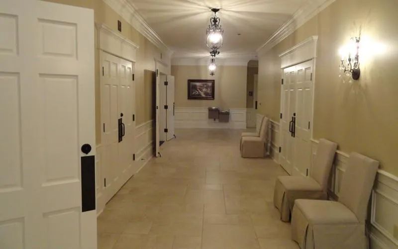 A quiet funeral home hallway with upholstered chairs and warm wall lighting